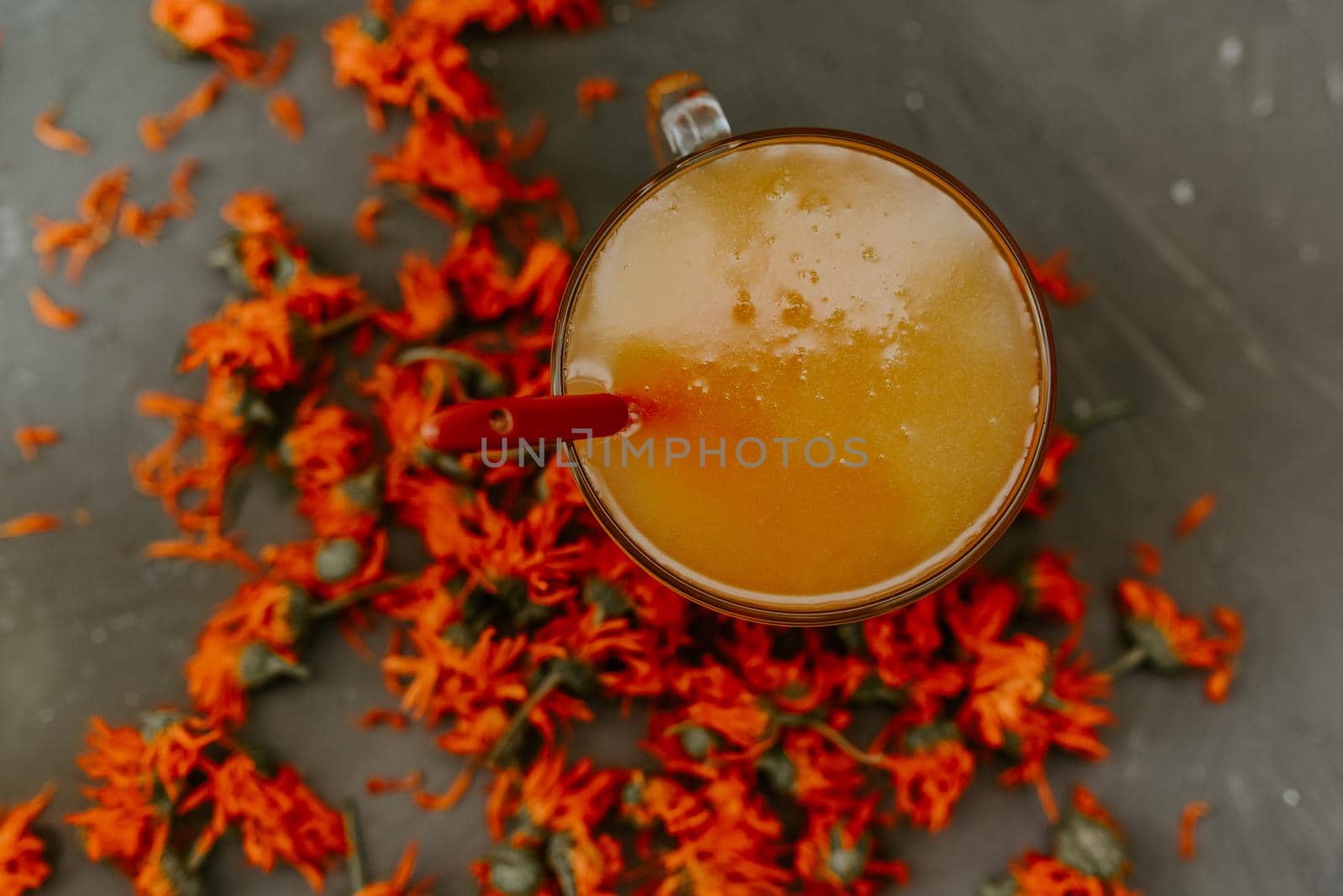 A small cup is filled to the top with yellow liquid honey, orange calendula. by AndriiDrachuk