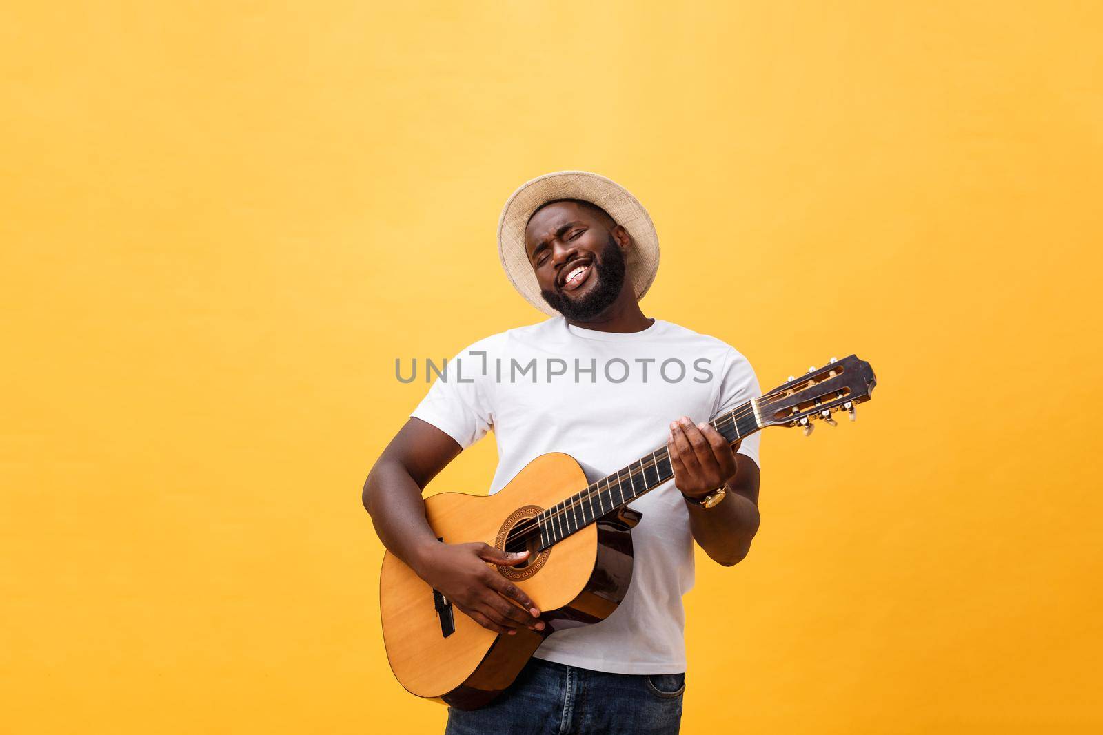 Muscular black man playing guitar, wearing jeans and white tank-top. Isolate over yellow background. by Benzoix