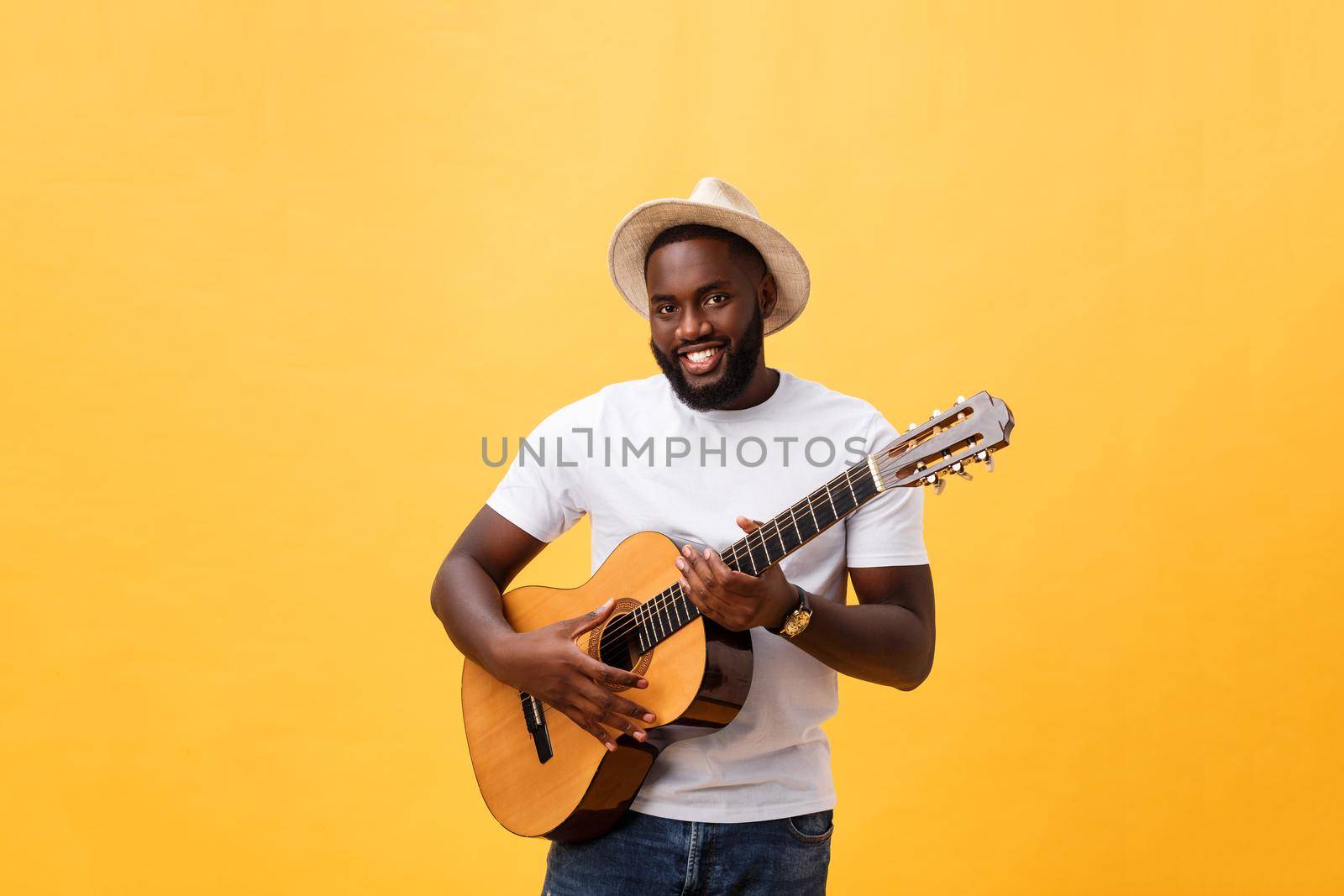 Muscular black man playing guitar, wearing jeans and white tank-top. Isolate over yellow background. by Benzoix