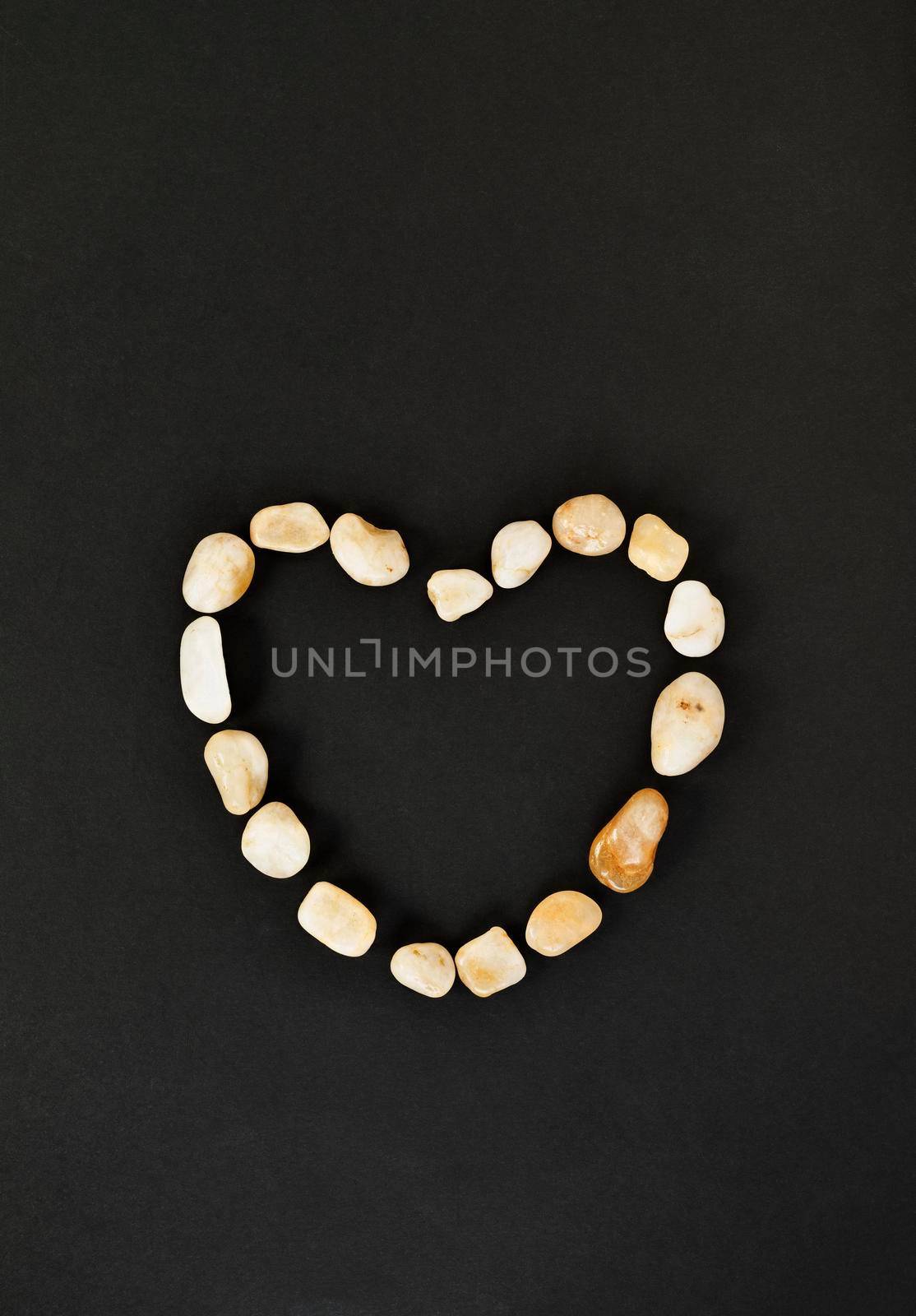  Heart shape with pebbles on black background , passion and love