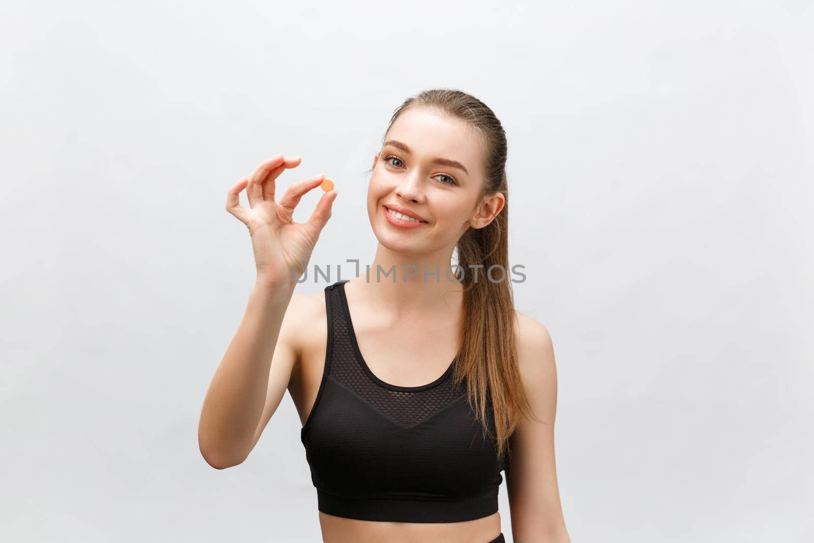 Supplements, Sports, Vitamins, Diet, Nutrition, Healthy Eating, Lifestyle. Close up of smiling fitness woman taking pill with cod liver oil Omega-3 , vitamin D, E, A fish oil capsules by Benzoix