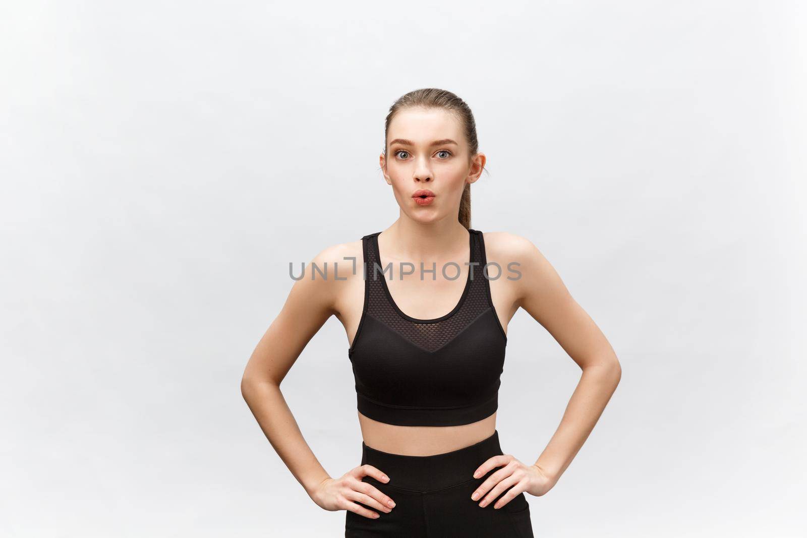 Attractive young adult in sportswear posing on white background. Sexy and sensual brunette woman with perfect body posing in studio isolated over white background with copyspace.