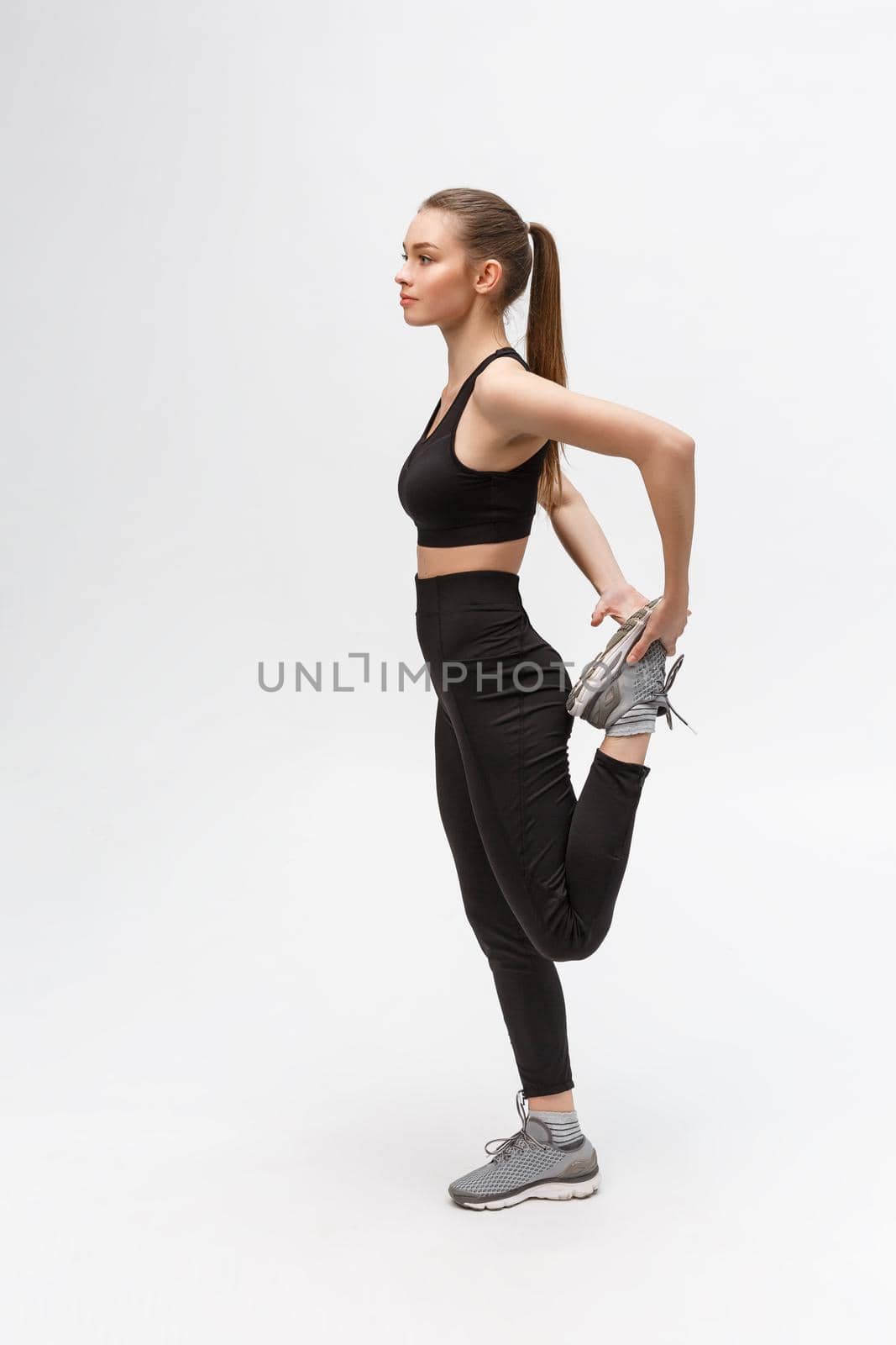 Portrait of happy sports woman stretching legs on the floor isolated on a white background