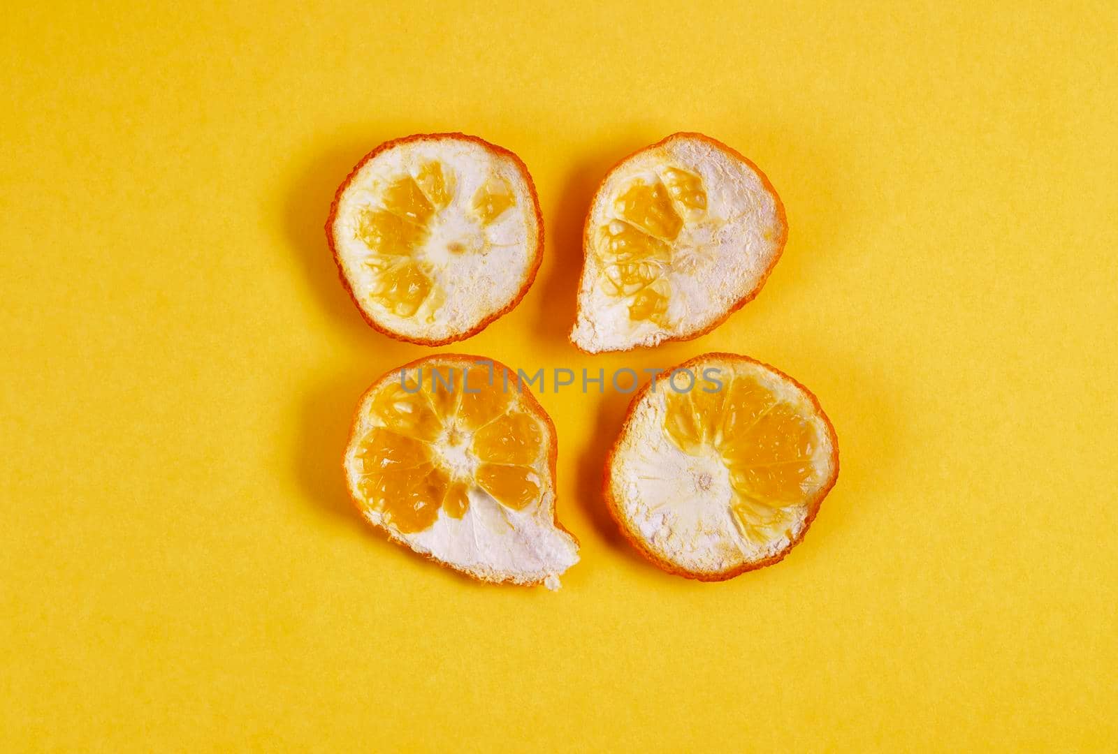 Several pieces of orange pell on yellow background