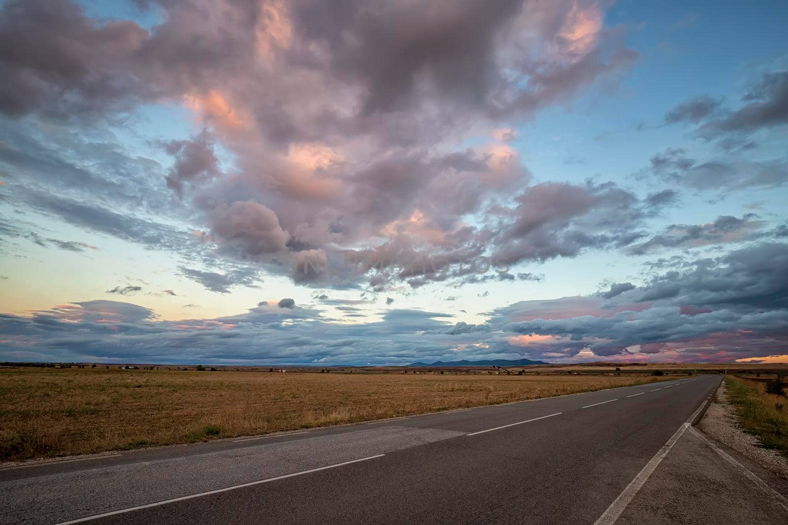 Amazing sunset over the road and field after rain