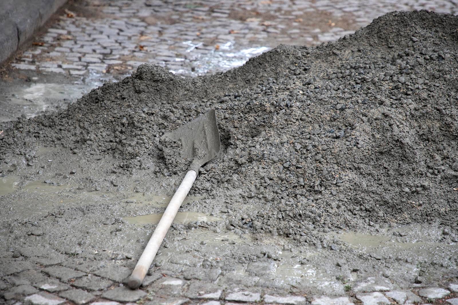 Hand mixing concrete mortar with shovel on construction site. 