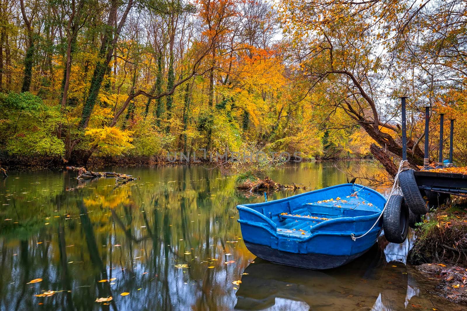 Boat with water reflection in the colorful autumn at a river pier 