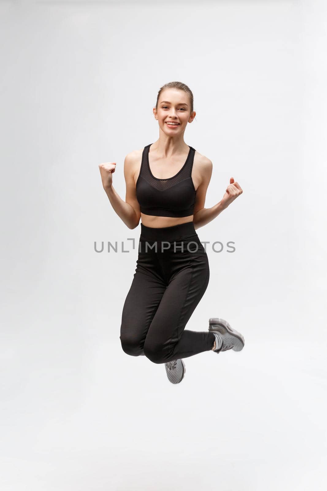 Full length picture of happy beautiful fitness woman over gray background.