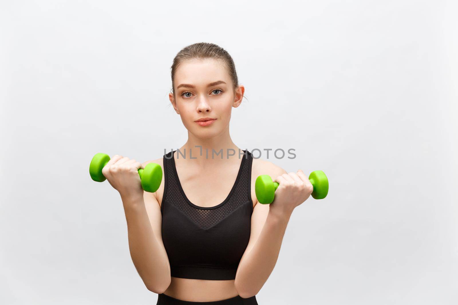 Happy fitness woman lifting dumbbells smiling cheerful, fresh and energetic. Caucasian fitness girl training isolated on white background. by Benzoix