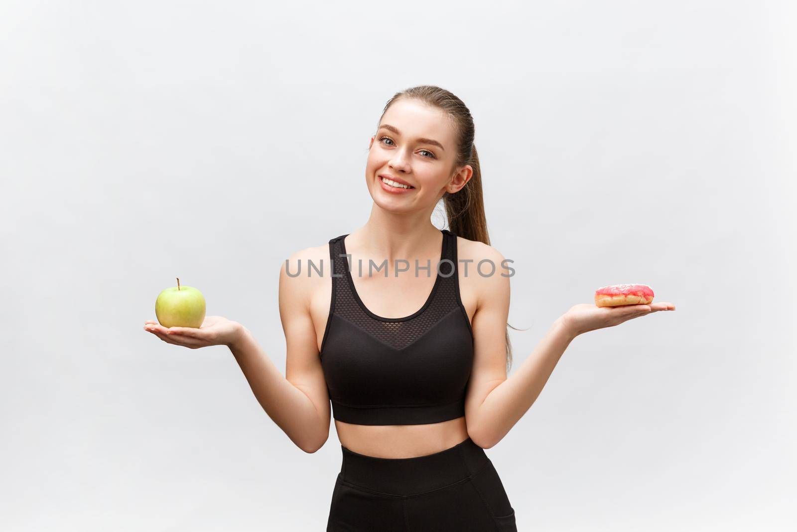 Young woman choosing between donut and apple on white background. Diet food concept.