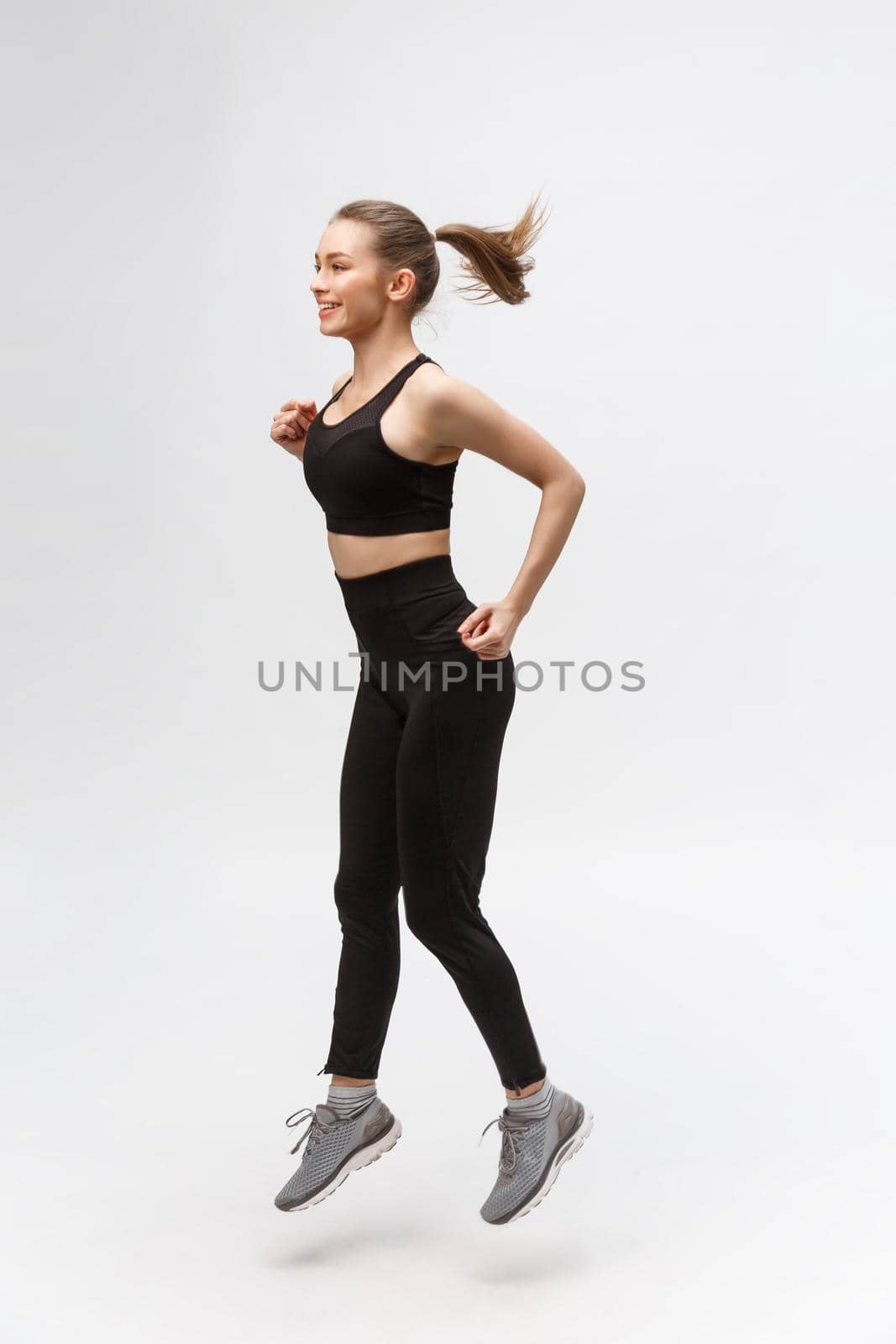 Full length picture of happy beautiful fitness woman over gray background.