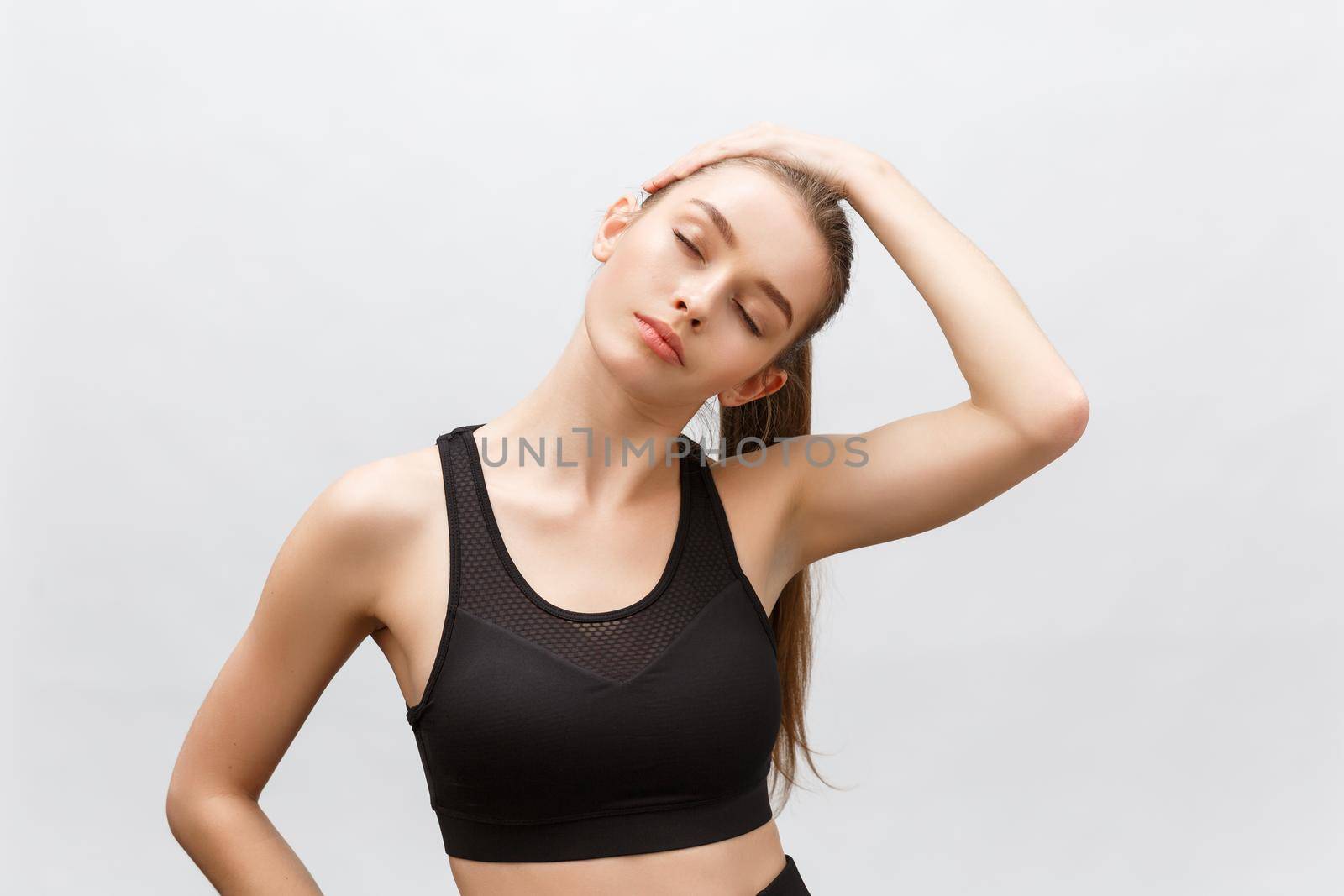 Young sporty beautiful woman stretching arms on side. Isolated over white background.