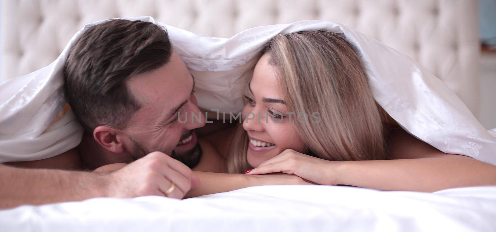 close up. cute loving couple lying under the blanket