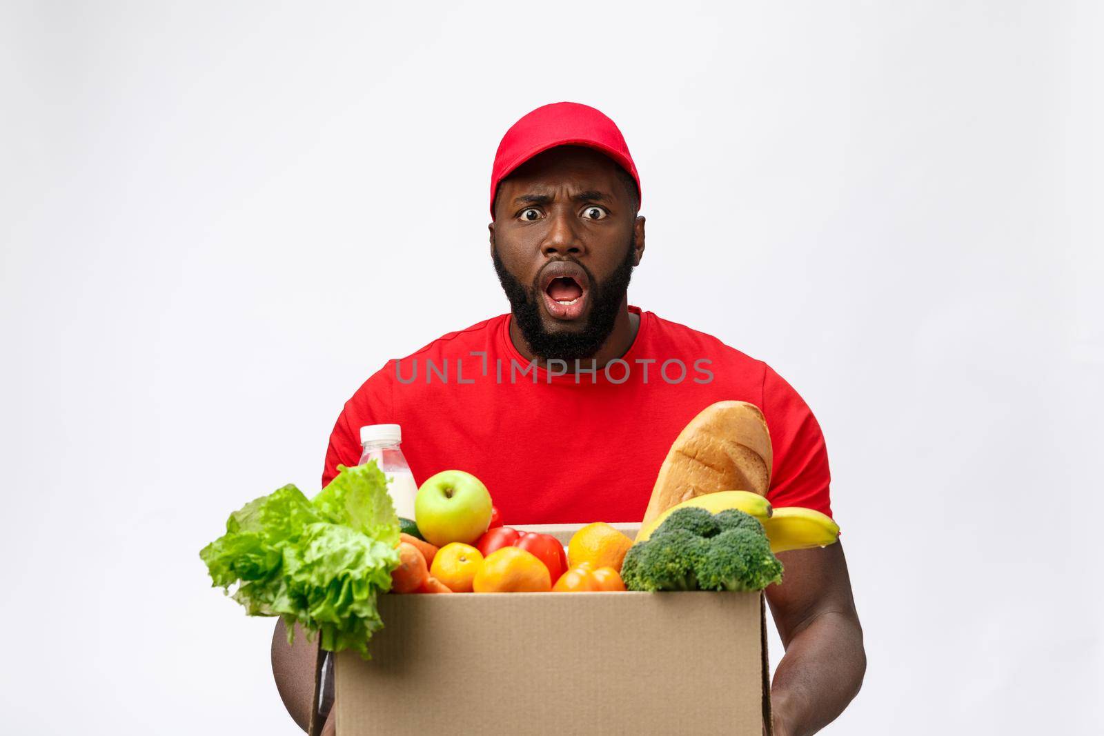 Young african american man holding grocery box in hands with shocking face. Isolated over Grey background
