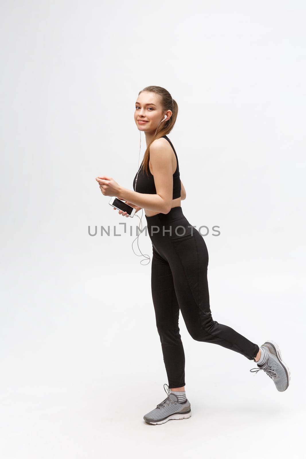 Sport woman. Young beautiful woman in sport clothes. Portrait full length sitting in headphones listening music