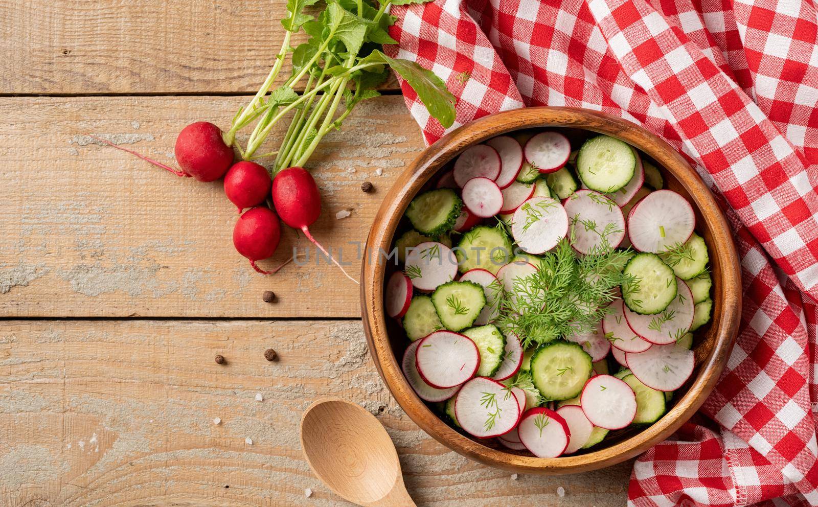 Bowl of healthy vegetarian salad with radish cucumber and fennel. top view on wooden background with copy space, summer food