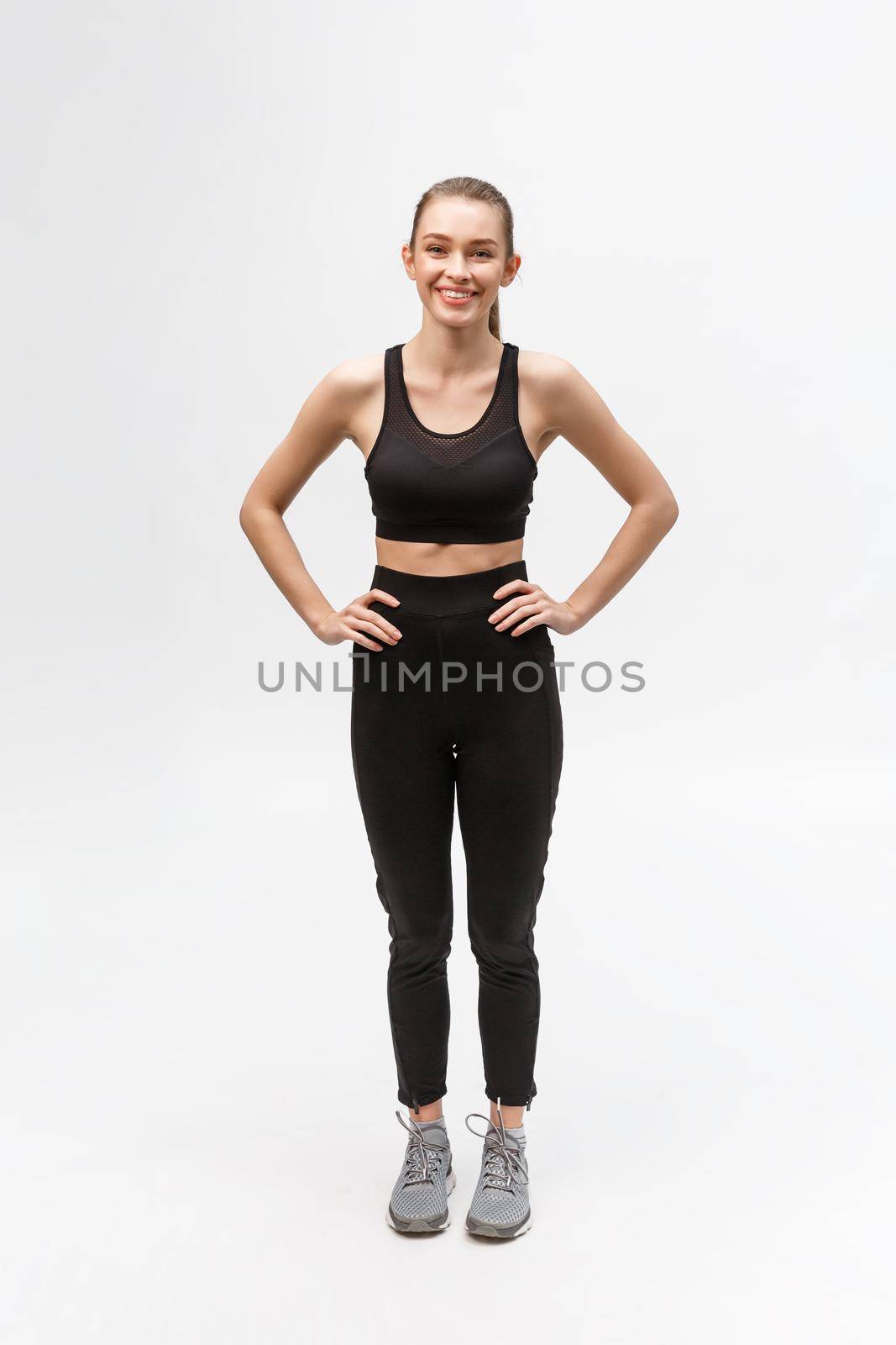 Attractive young adult in sportswear posing on white background. Sexy and sensual brunette woman with perfect body posing in studio isolated over white background with copyspace.