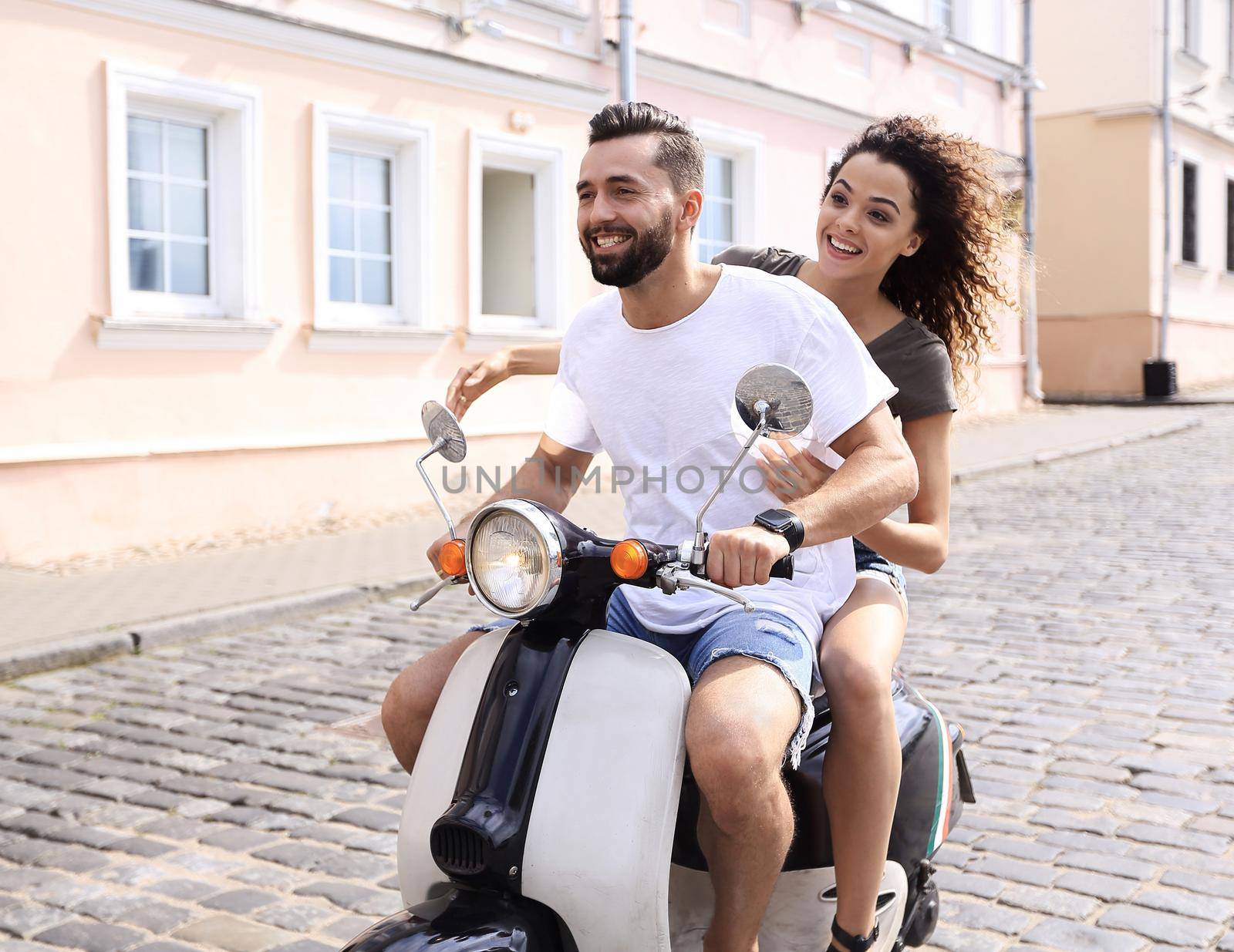 Happy cheerful couple riding vintage scooter outdoors.