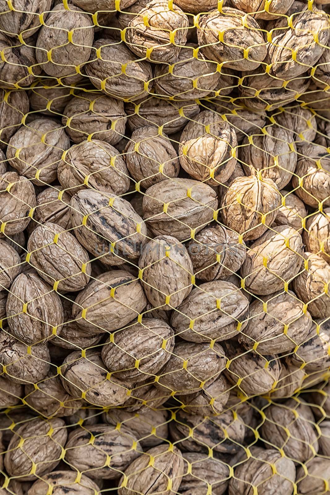 Lots of walnuts in a net bag at a market. Vertical view