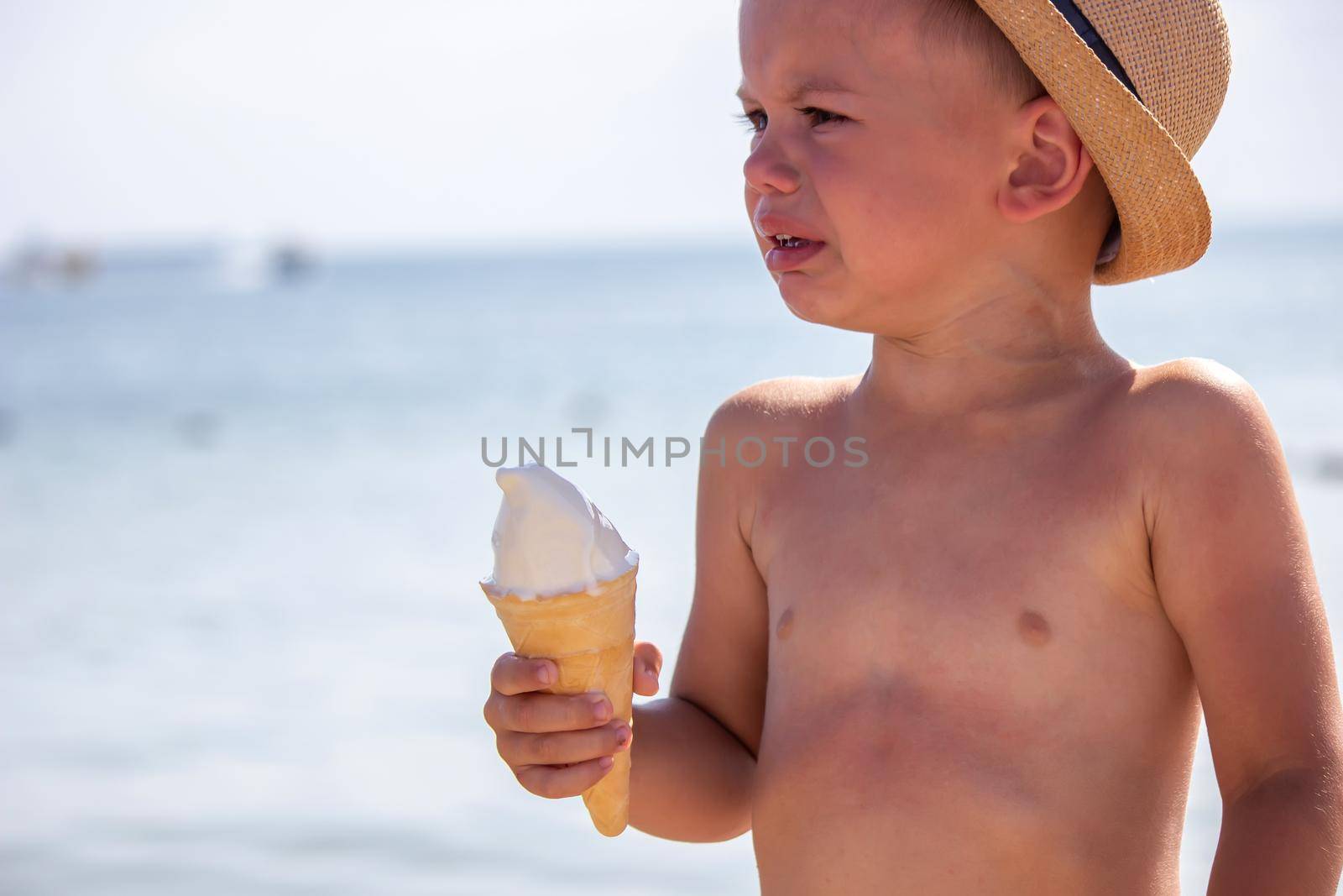 the child cries and eats ice cream on the beach. selective focus