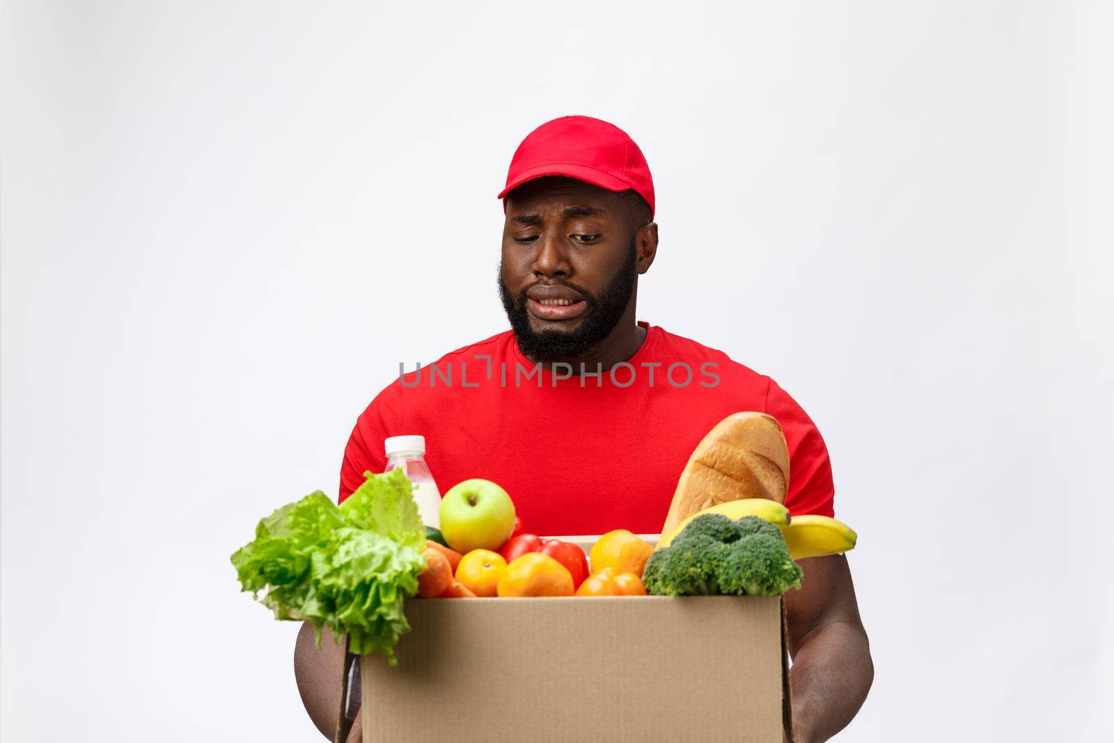 Portrait of delivery african american man in red shirt. he lifting heavy weight grocery boxes against having a isolated on the white background