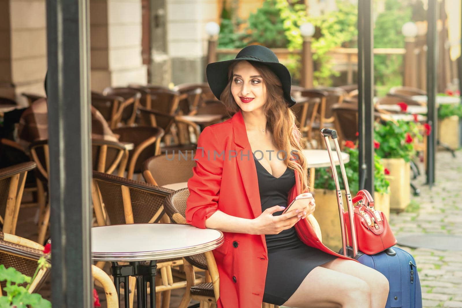 Outdoor shot of fashionable woman sitting at table in outside cafe.