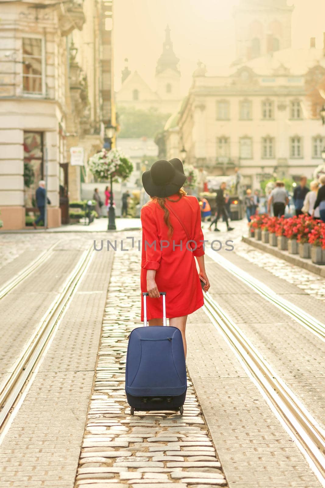 Beautiful young girl walking with blue suitcase. by okskukuruza