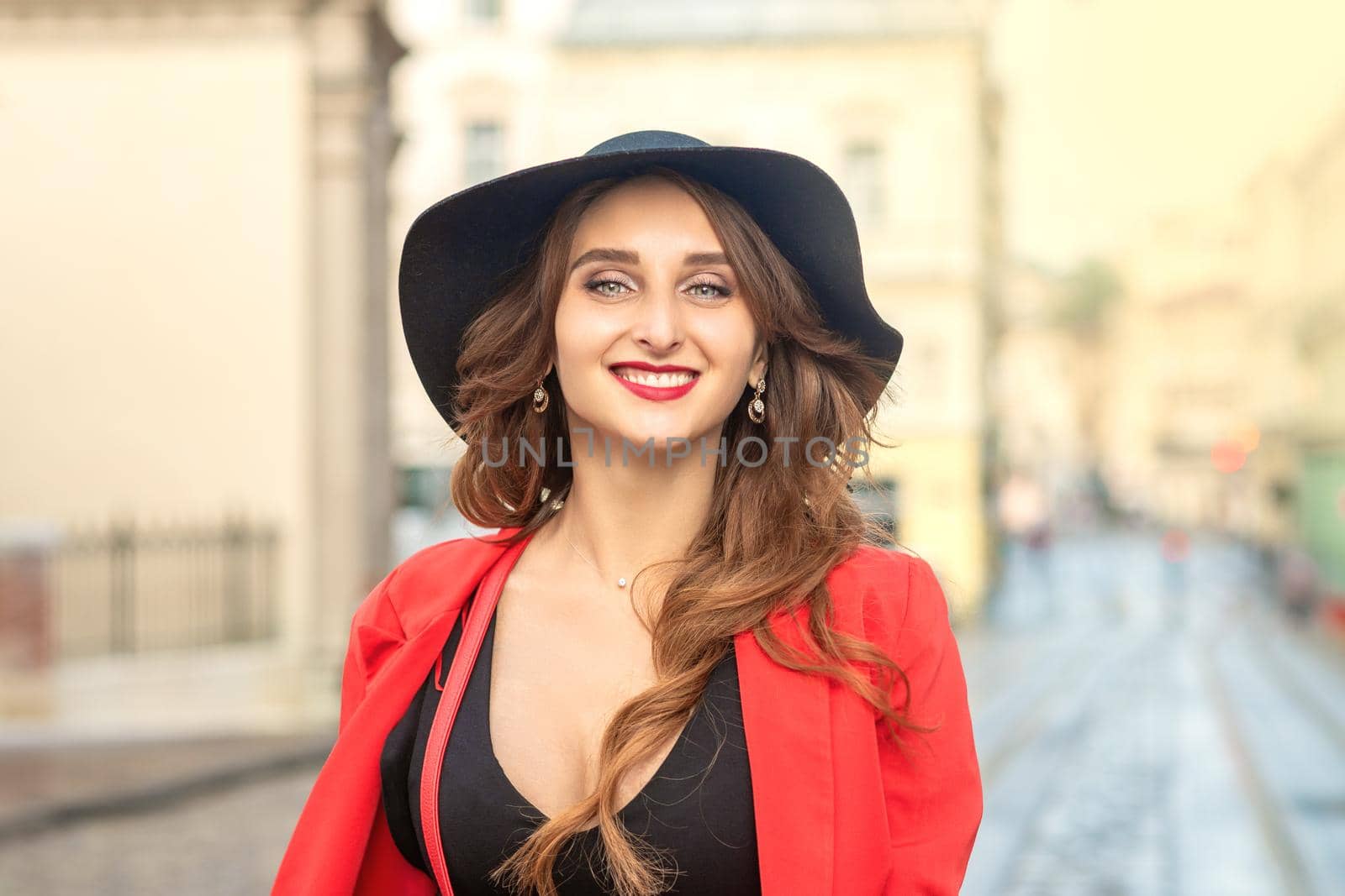 Outdoor portrait of young elegant fashionable woman wearing trendy hat walking in street of European city.