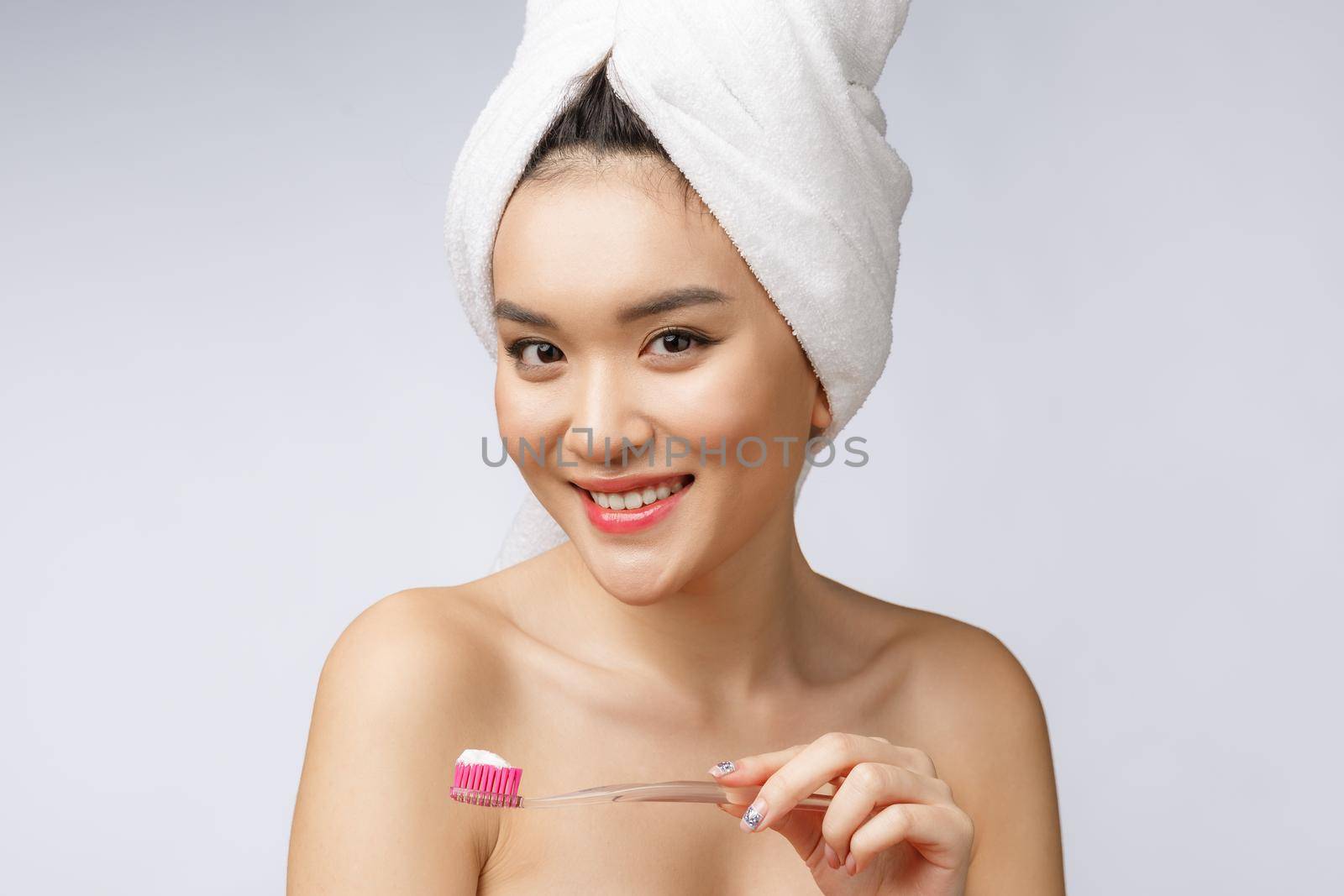 Beautiful young woman on white isolated background holds a toothbrush, Asian.