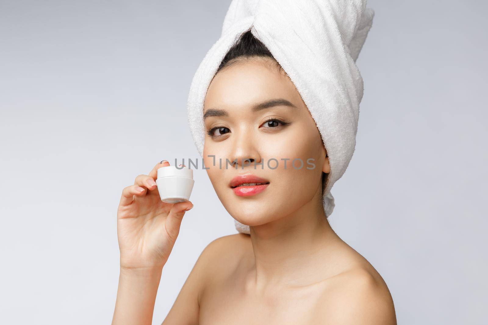 health and beauty concept - Attractive asian woman applying cream on her skin, isolated on white