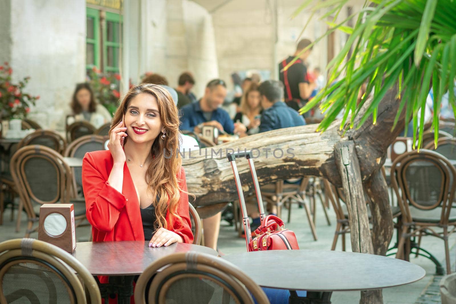 Business woman is talking by mobile phone while sitting at the cafe outdoors.