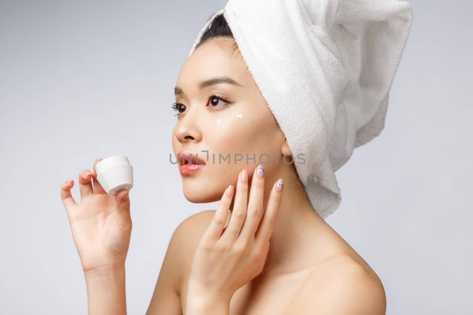 health and beauty concept - Attractive asian woman applying cream on her skin, isolated on white