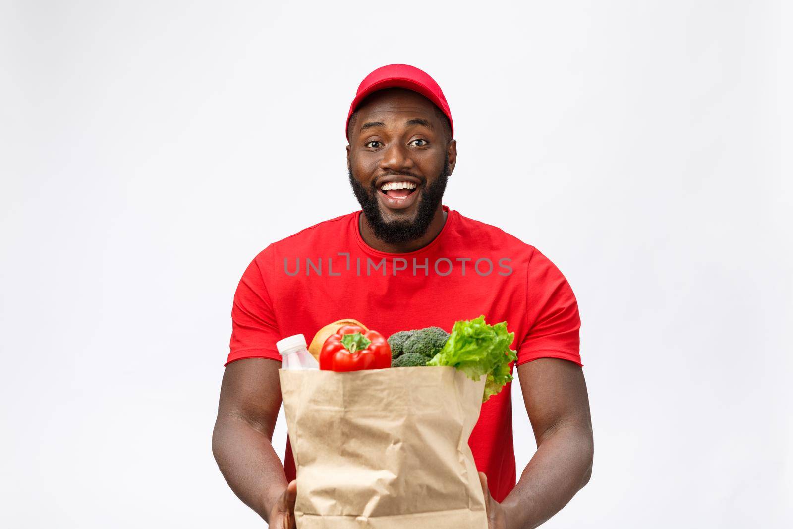 Delivery Concept - Handsome African American delivery man carrying package grocery food and drink from store. Isolated on Grey studio Background. Copy Space