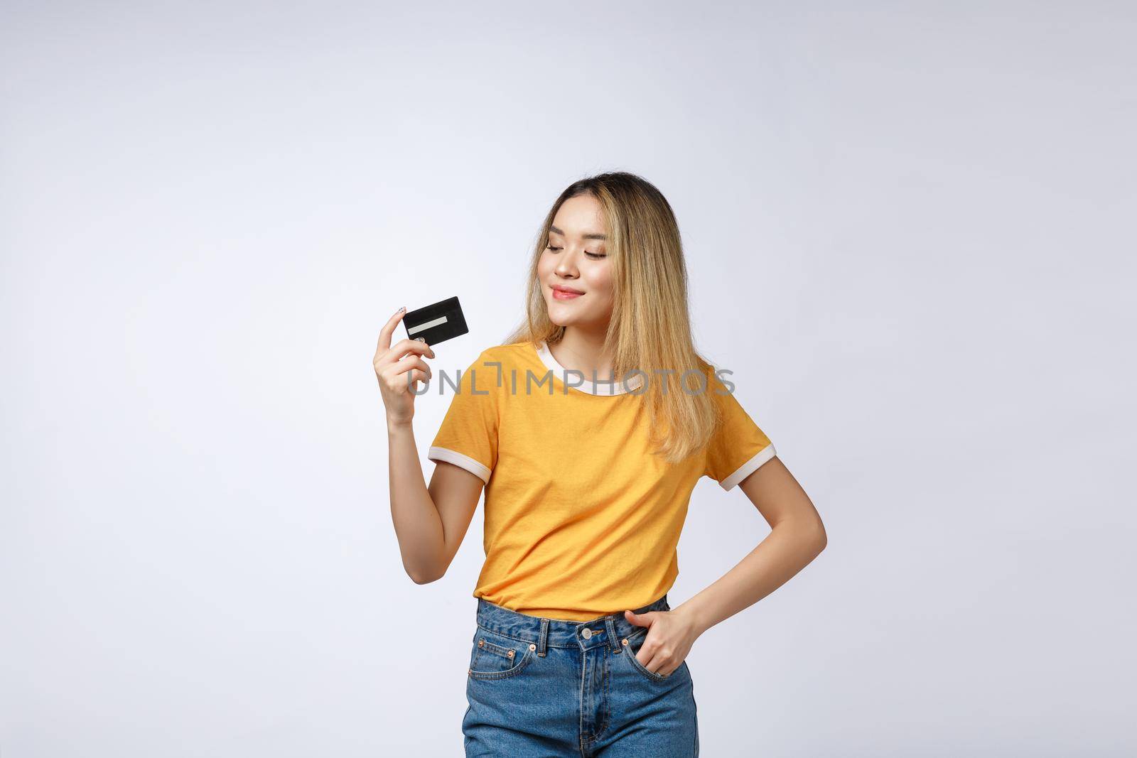 Asian content woman holding fan of money dollar banknotes and credit card and looking on copyspace isolated over gray background