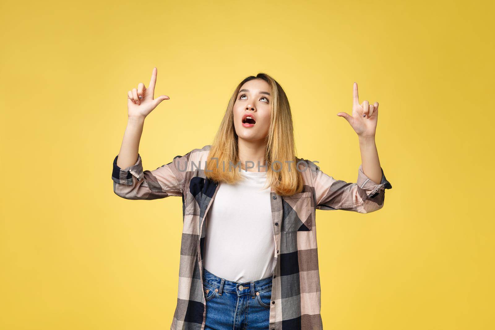 Smiling woman pointing finger side. Isolated portrait on yellow