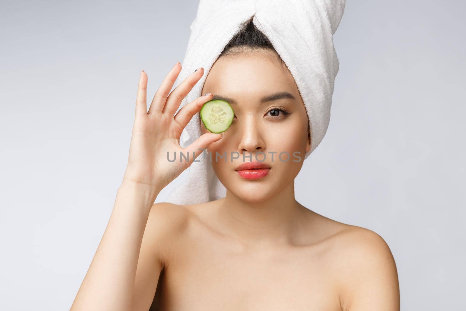 Young asian woman with cucumber slice in her hands isolated on white background