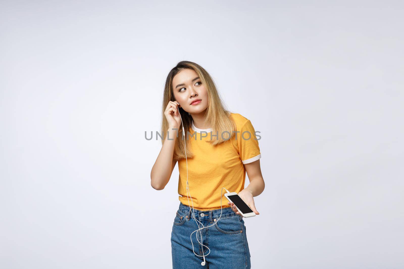 Portrait of a joyful satisfied asian woman in headphones listening to music and jumping isolated over white background.