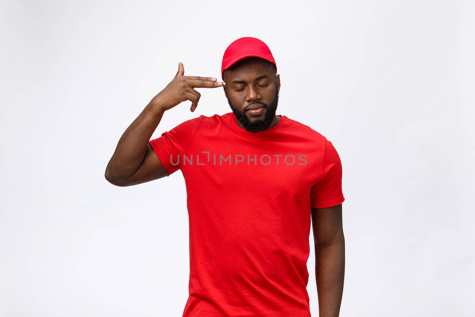 Delivery Concept - Portrait of Serious African American delivery man showing silly aggressive expression and unhappy. Isolated on Grey studio Background. Copy Space. by Benzoix