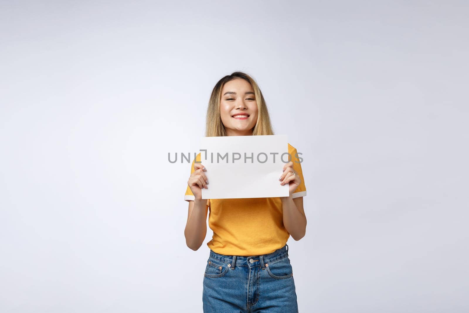 Excited woman showing empty blank paper card sign with copy space for text. Gorgeous multi ethnic Chinese Asian and white Caucasian female model isolated on white background.