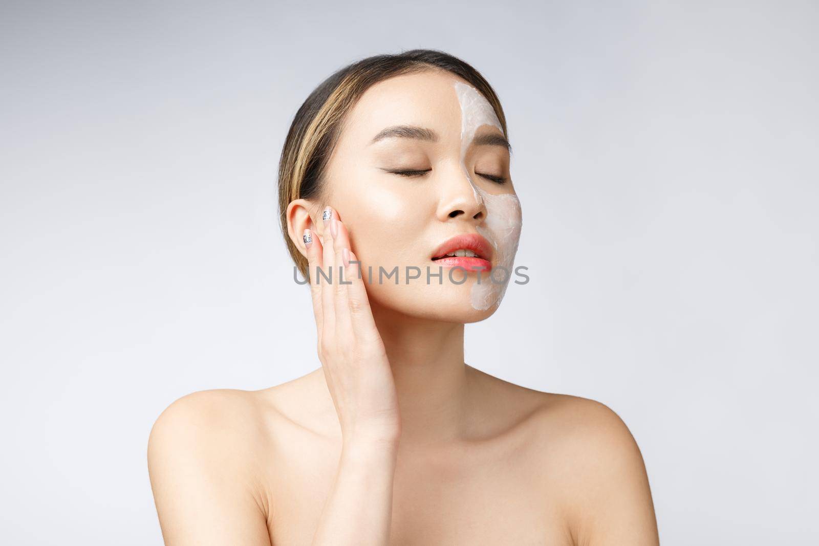 Charming pleasant woman applying cream on half face