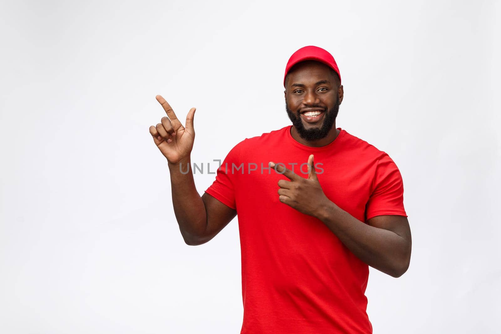 Delivery Concept - Portrait of Happy African American delivery man pointing hand to present something. Isolated on Grey studio Background. Copy Space by Benzoix