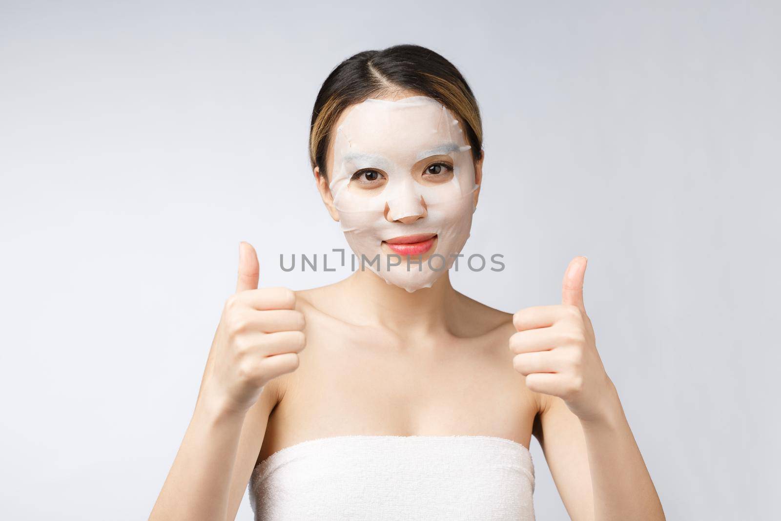 Spa, healthcare. Asian girl with a cosmetic mask with showing thumb up. by Benzoix