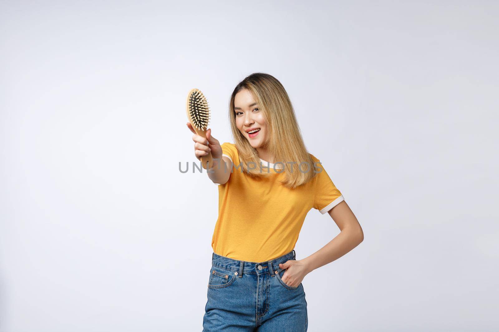 young beautiful woman combing her hair isolated over grey background