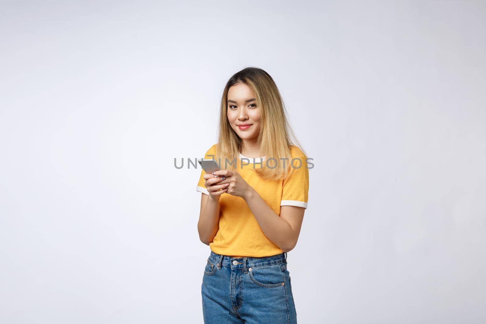 Woman look and texting with friend on mobile phone isolated over grey background