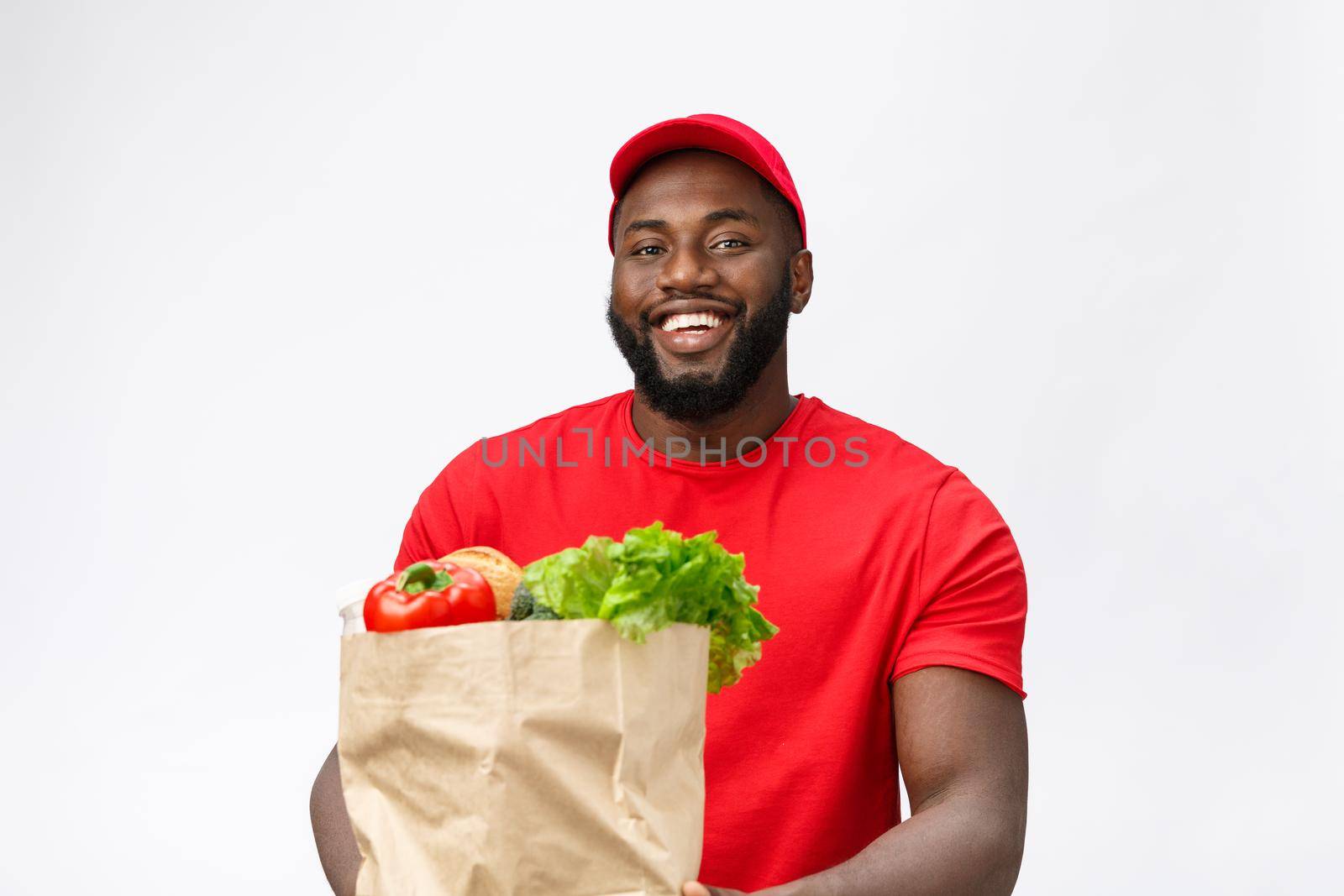 Delivery Concept - Handsome African American delivery man carrying package grocery food and drink from store. Isolated on Grey studio Background. Copy Space.