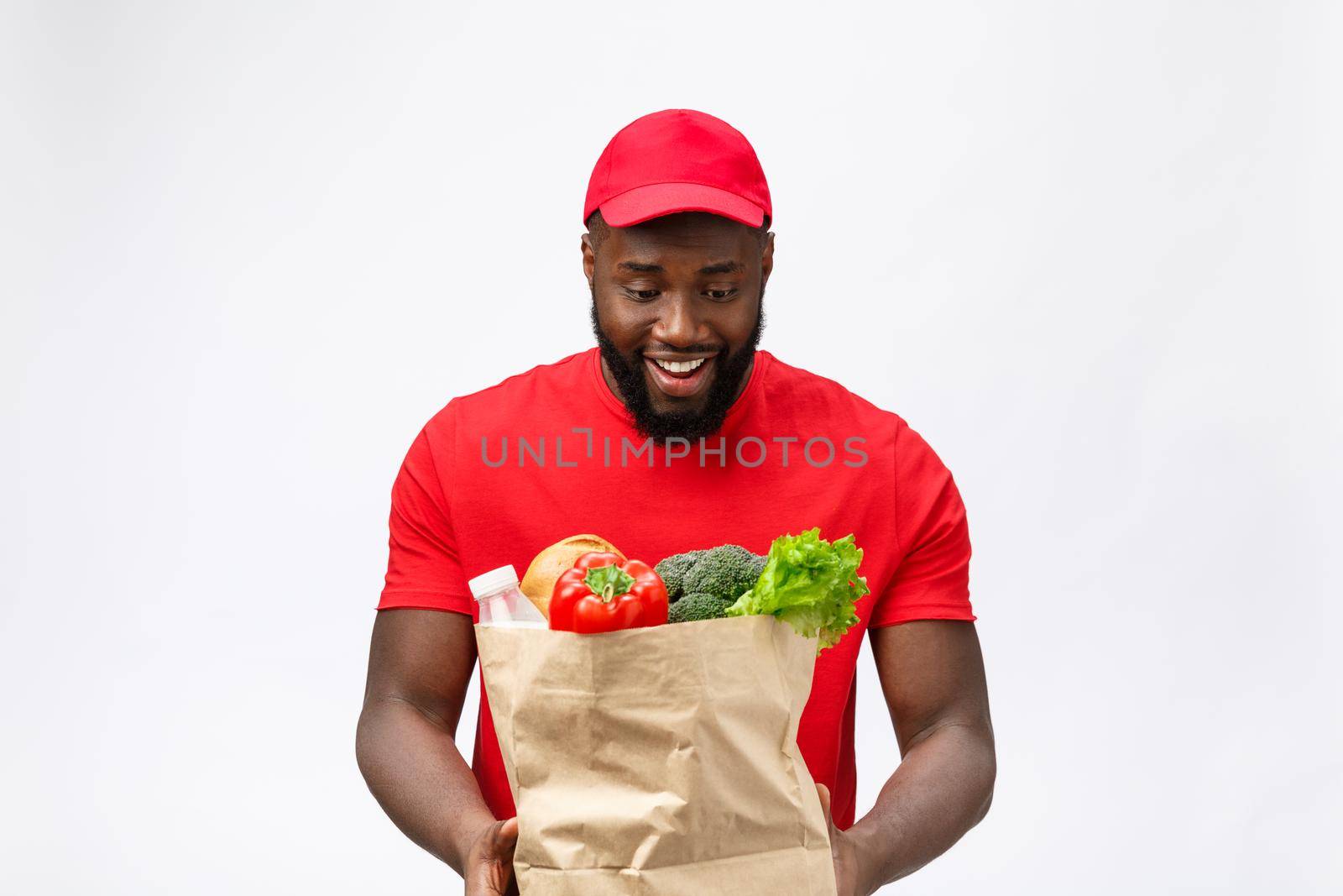 Young african american man holding grocery package in hands with shocking face. Isolated over Grey background