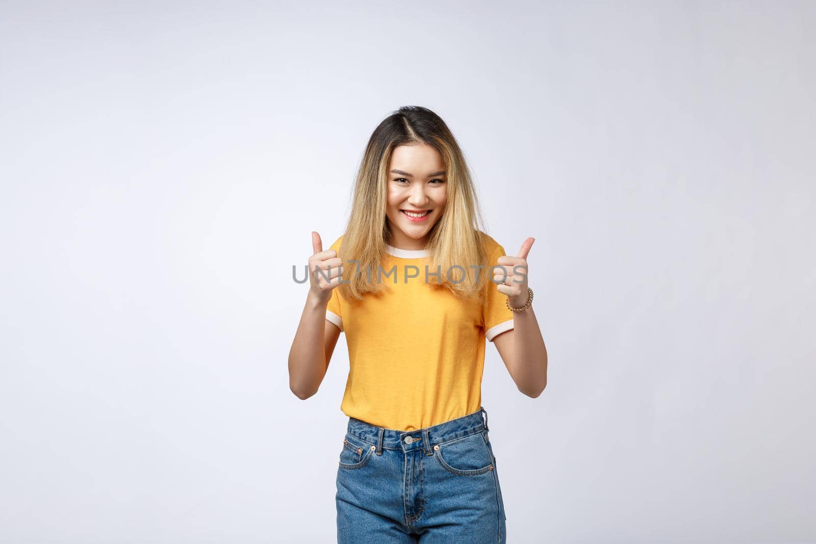 Young Asian woman show thumbs up on white background. by Benzoix