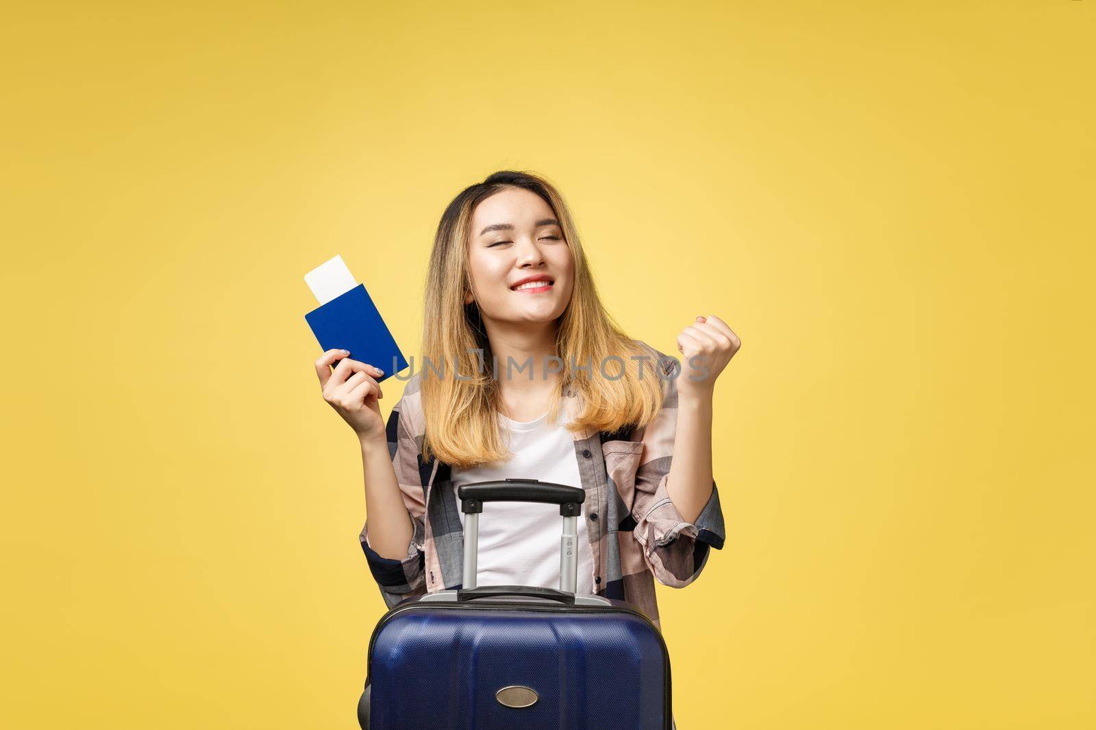 Woman travel. Young beautiful asian woman traveler holding passport ,suitcase and air ticket standing over yellow