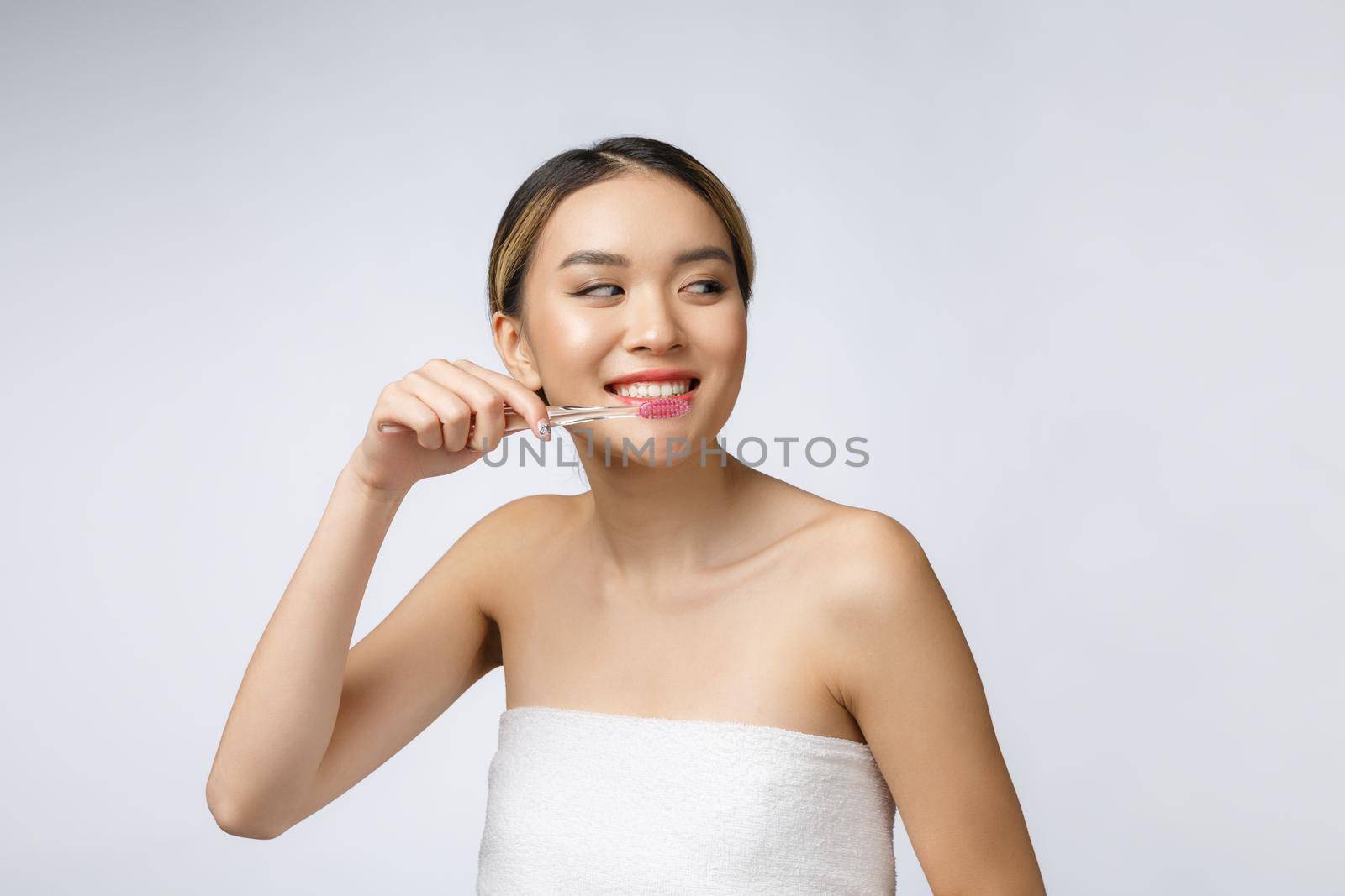 Beautiful young woman on white isolated background holds a toothbrush, Asian.