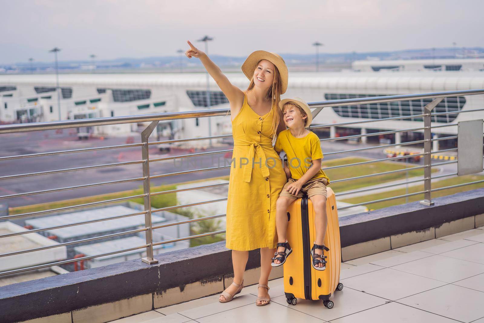 Family at airport before flight. Mother and son waiting to board at departure gate of modern international terminal. Traveling and flying with children. Mom with kid boarding airplane. yellow family look by galitskaya